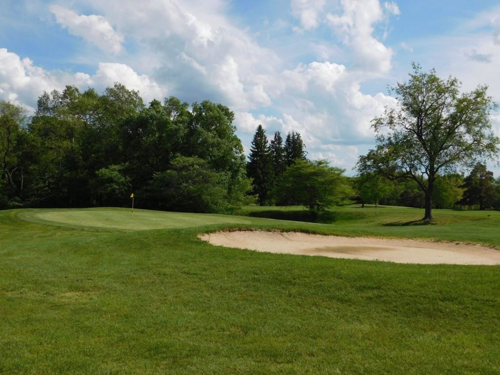 green flanked by a bunker and trees