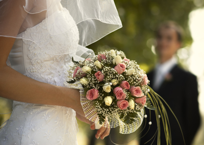 bride holding bouquet while groom watches in the background